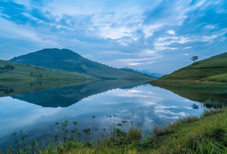 a lake surrounded mountains and grass background